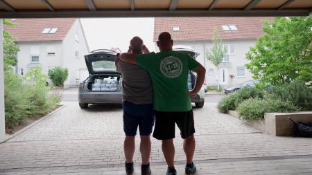 Dirk und Ralf erfreuen sich stolz an dem Anblick von zwei Elektroauto-Kofferräumen voll mit selbstgebautem Scientific Gear.